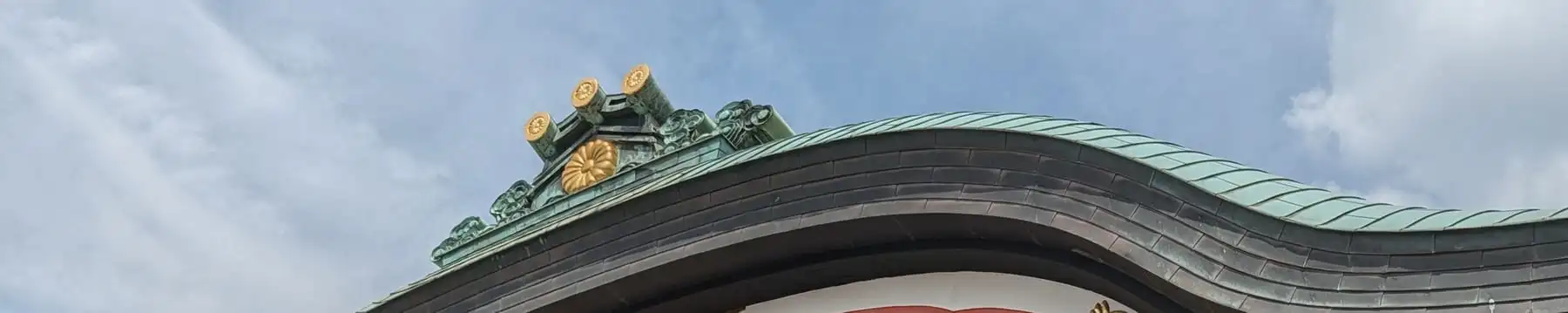 The curved gable roof of a shrine hall hung with paper streamers